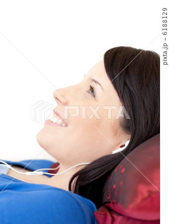 Cheerful teen girl listening music lying on a sofa Cheerful teen girl listening music lying on a sofa 6188129