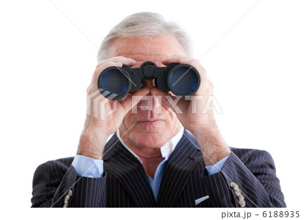 Serious businessman looking through binoculars standing 6188935
