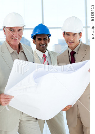 Smiling architects with hardhat looking at blueprints Smiling architects with hardhat looking at blueprints 6189415