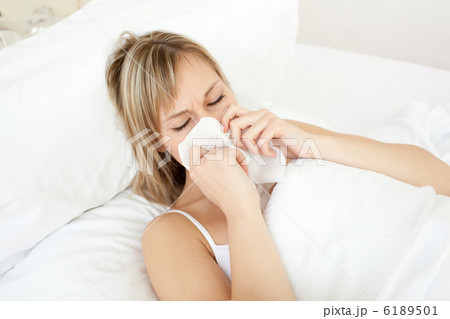 Sick woman blowing lying on her bed Sick woman blowing lying on her bed 6189501