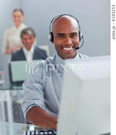 Confident businessman with headset on working at a computer Confident businessman with headset on working at a computer 6193253