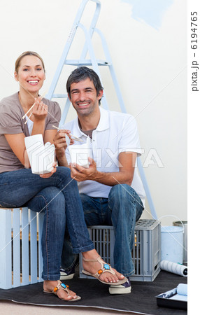 Smiling couple eating while decorating a room 6194765