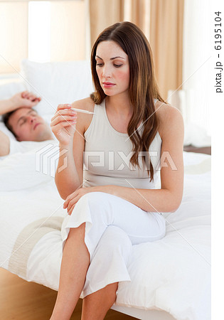 Caring woman taking her sick husband's temperature Caring woman taking her sick husband's temperature 6195104