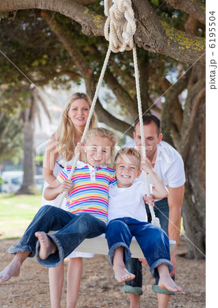 Joyful parents pushing their children on a swing Joyful parents pushing their children on a swing 6195504