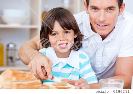 Portrait of a father and his son spreading jam on bread 6196211