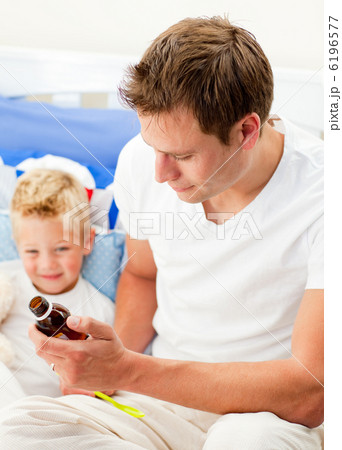 Attractive father giving cough syrup to his sick son 6196577