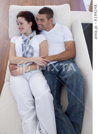 Couple lying on sofa watching television Couple lying on sofa watching television 6199248