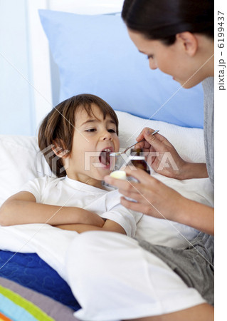 Mother giving her son syrup 6199437