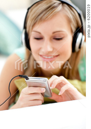 Attractive blond woman listening music lying on a sofa Attractive blond woman listening music lying on a sofa 6200019