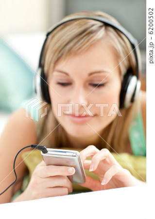 Pretty young woman listening music lying on a sofa Pretty young woman listening music lying on a sofa 6200502