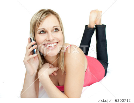 Happy woman talking on phone lying on a bed Happy woman talking on phone lying on a bed 6200712