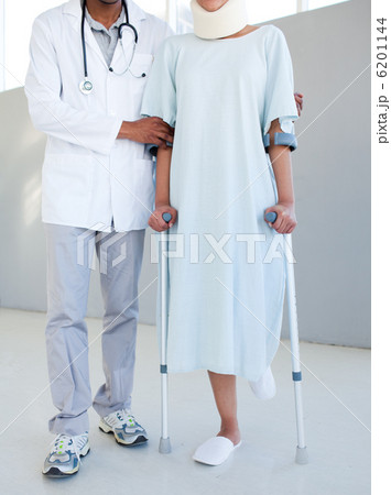A physical therapist helping a patient with neck brace and on cr A physical therapist helping a patient with neck brace and on cr 6201144