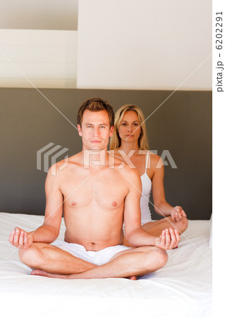 Young couple doing yoga on bed with copy-space Young couple doing yoga on bed with copy-space 6202291