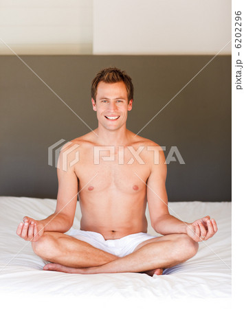 Smiling handsome man meditating on bed 6202296