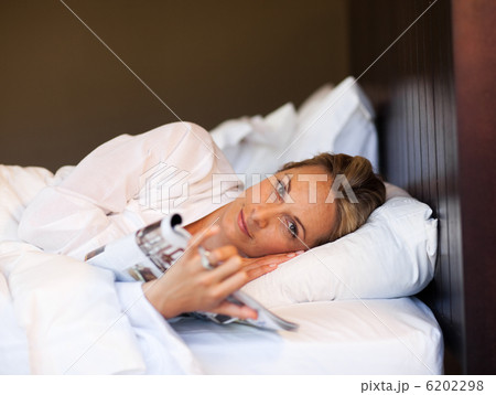 Young woman reading a magazine in bed Young woman reading a magazine in bed 6202298