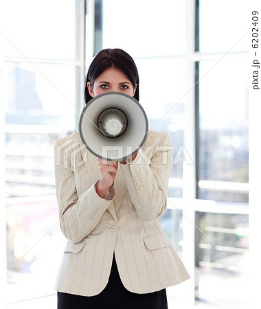 Businesswoman shouting through megaphone to the camera Businesswoman shouting through megaphone to the camera 6202409