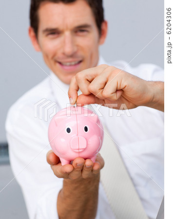 Attractive businessman saving money in a piggybank 6204306