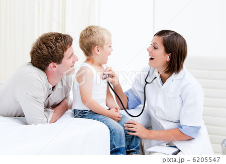 Radiant female doctor examining a little boy with his father 6205547