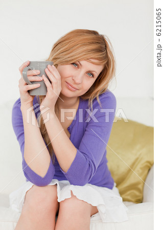 Pretty red-haired woman holding a cup of coffee and posing while 6215065