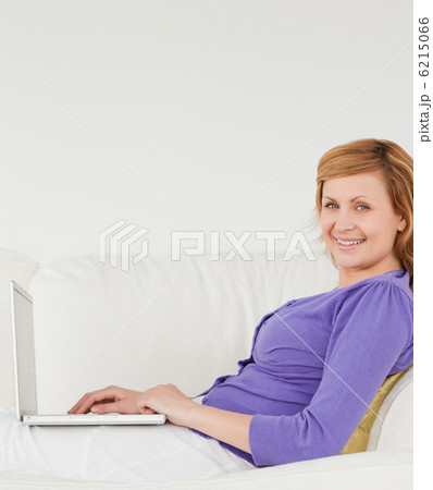 Good looking red-haired woman using a laptop and posing while ly 6215066