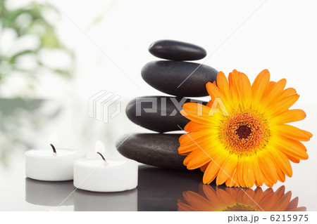 Lighted candles pebble stack an orange gerbera Lighted candles pebble stack an orange gerbera 6215975