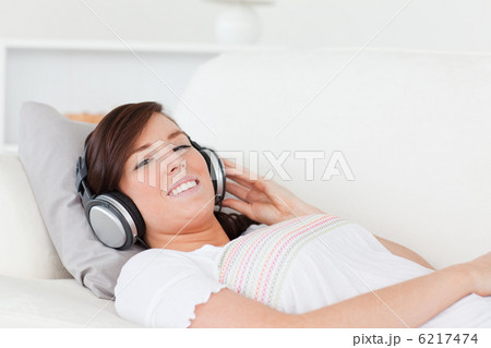 Pretty brunette female relaxing with her headphones while lying 6217474