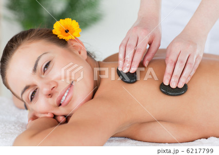Close up of a smiling woman enjoying a hot stone massage Close up of a smiling woman enjoying a hot stone massage 6217799