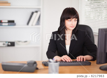 Beautiful brunette woman working on a computer while sitting at Beautiful brunette woman working on a computer while sitting at 6217963