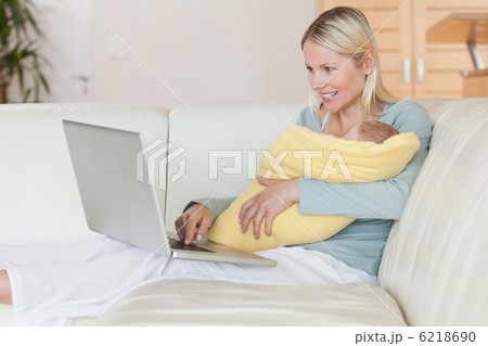 Mother with laptop on the couch holding her baby 6218690