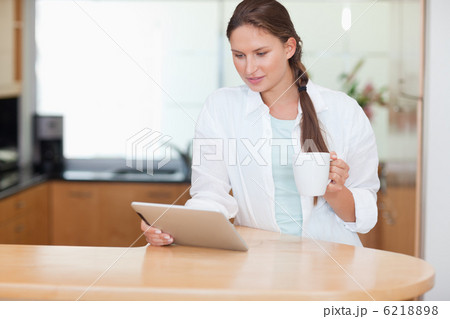 Woman using a tablet computer while drinking tea 6218898