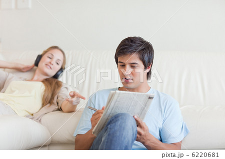 Woman helping her fiance to do crosswords while listening to mus 6220681