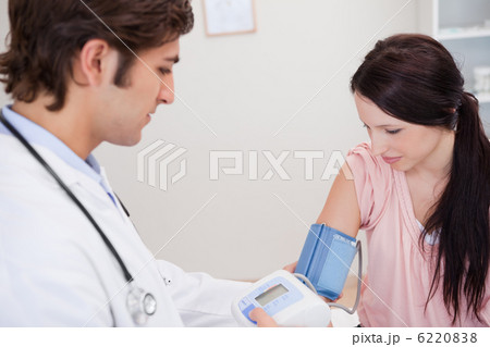 Male doctor taking female patients blood pressure 6220838
