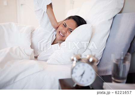 Woman covering her ears cause of ringing alarm clock 6221657
