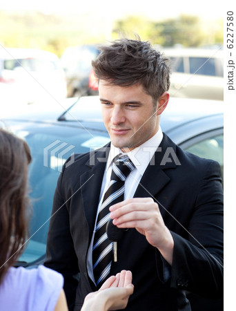 Young salesman giving car's key Young salesman giving car's key 6227580