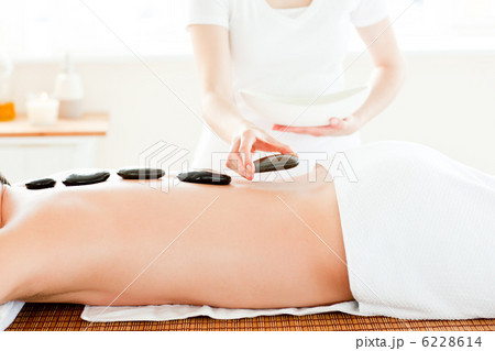 Close-up of a young man receiving hot stone on his back Close-up of a young man receiving hot stone on his back 6228614