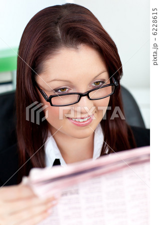 Glowing young businesswoman reading a newspaper 6228615
