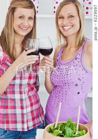 Two radiant women drinking wine after cooking in the kitchen 6229097