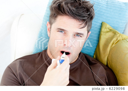 Diseased young man holding a thermometer looking at the camera 6229098