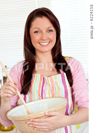 Smiling woman cooking a cake at home 6229158