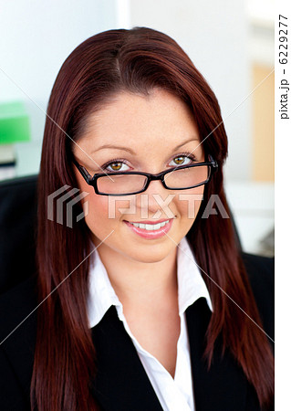 Bright businesswoman holding her glasses sitting in her office 6229277