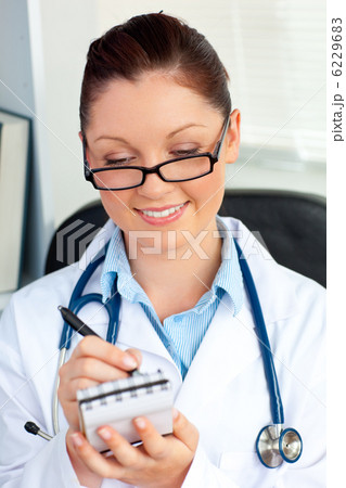 Confident female doctor smiling at the camera holding a notepad Confident female doctor smiling at the camera holding a notepad 6229683
