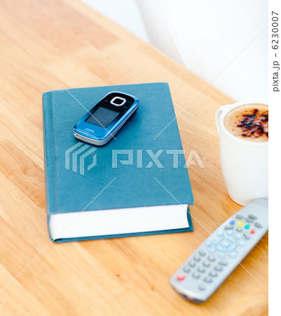 Close-up of a book,cellphone,remote and cup of coffee on the tab Close-up of a book,cellphone,remote and cup of coffee on the tab 6230007