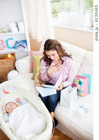 Bright woman sitting on the sofa with bags reading a card while 6230465