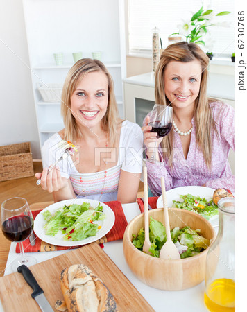 Pretty women eating a salad and drinking wine in the kitchen Pretty women eating a salad and drinking wine in the kitchen 6230768