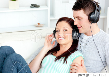 Charming couple listening to music with headphones lying on the 6231296