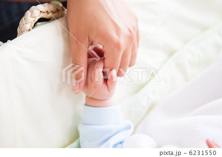 Close-up of a young mother holding the hand of her baby lying on 6231550