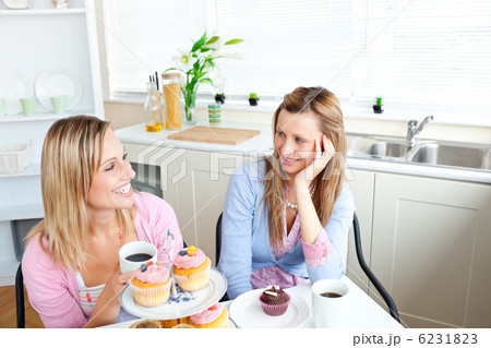 Two delighted female friends eating pastries and drinking coffee 6231823