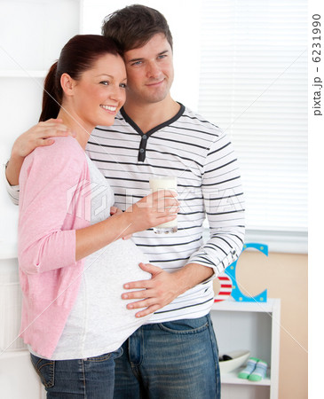 Portrait of a smiling pregnant woman holding a glass of milk and 6231990