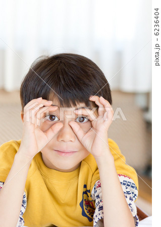 指で双眼鏡の形をしておどけるかわいい男の子の写真素材