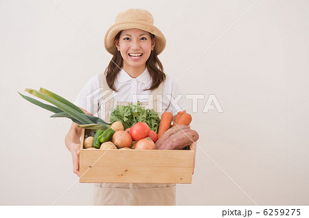 野菜の入った箱を持つ女性の写真素材